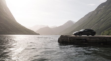 A Porsche Taycan by the quay at a beautiful fjord in Sunnmøre region