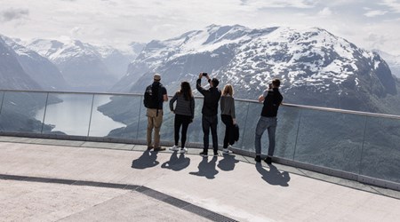 Group of friends enjoying the panoramic fjord and snow-covered mountain views 