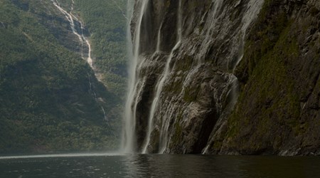 Close view of a powerful waterfall dropping into the fjord, surrounded by steep cliffs.