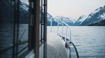 View from a boat gliding through a fjord, surrounded by steep snow-covered mountains