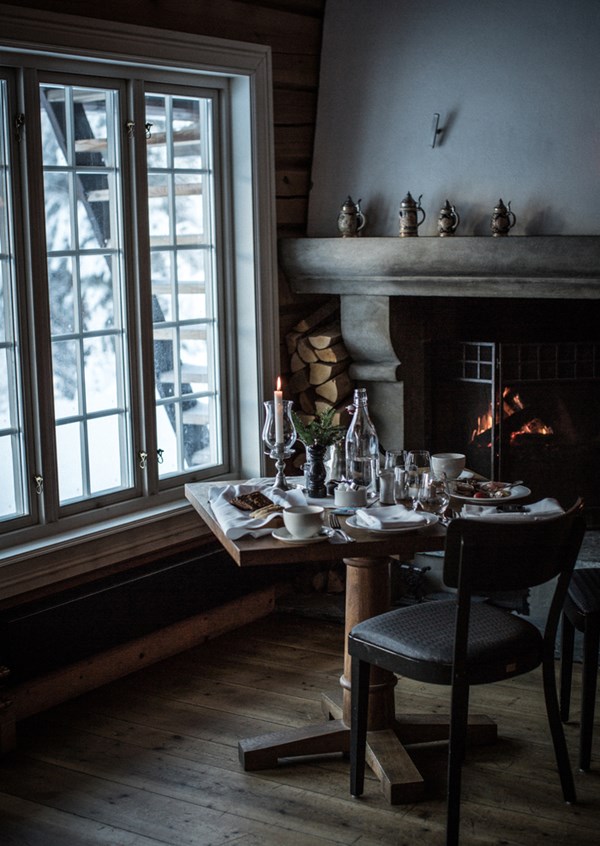 Cozy dining setting by the fireplace at Storfjord, table set with Norwegian cuisine and winter views.